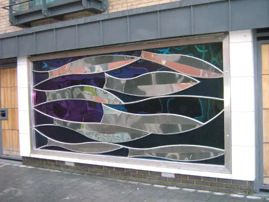 Steel sculpture of fish on the side of a building