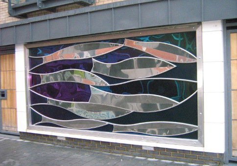 Steel sculpture of fish on the side of a building