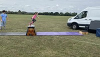 Girl jumping over old fashioned gym vaulting equipment set out in a large field preview
