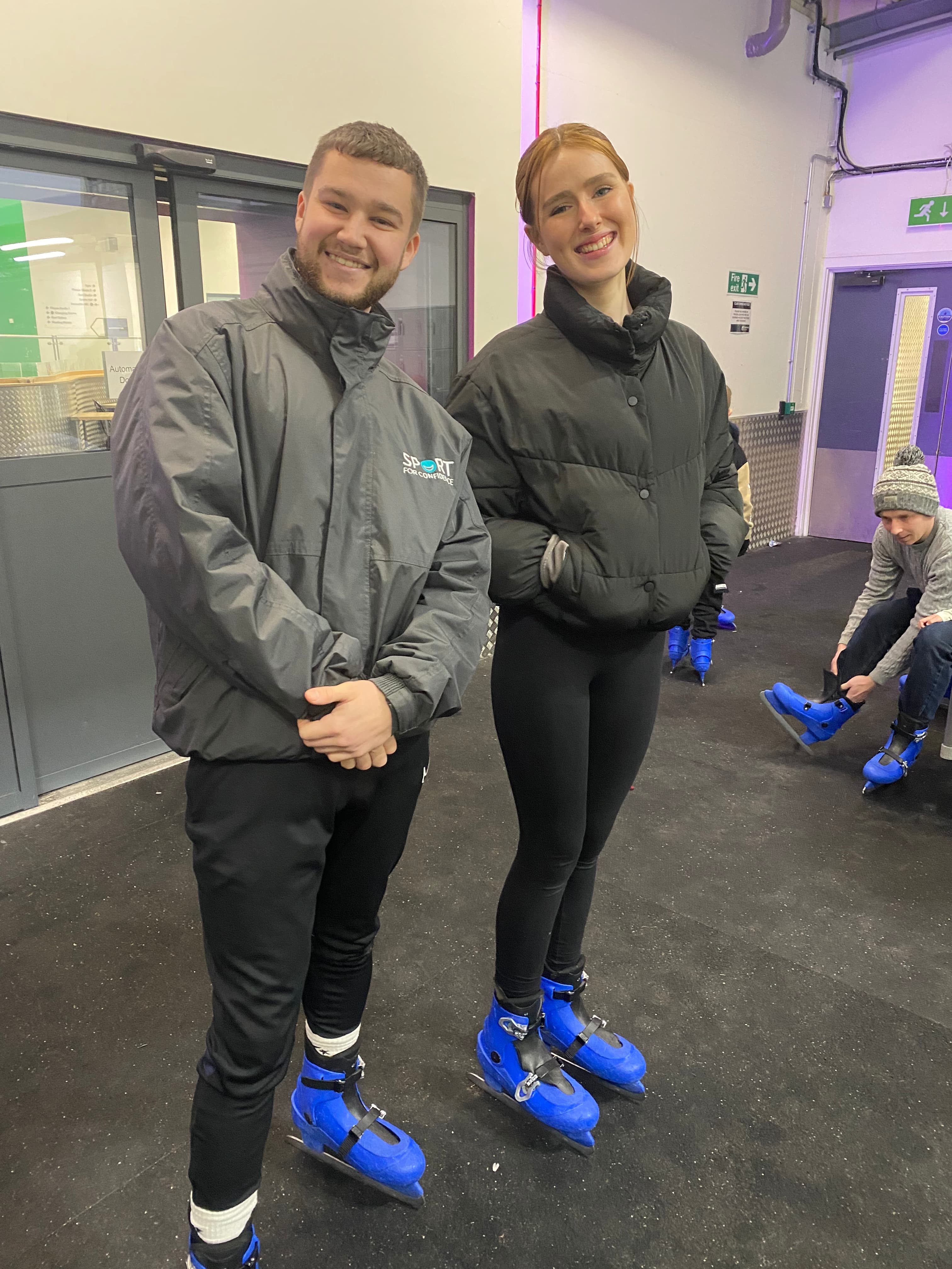 Two Sport for Confidence ice skating coaches stood side by side off-ice, smiling
