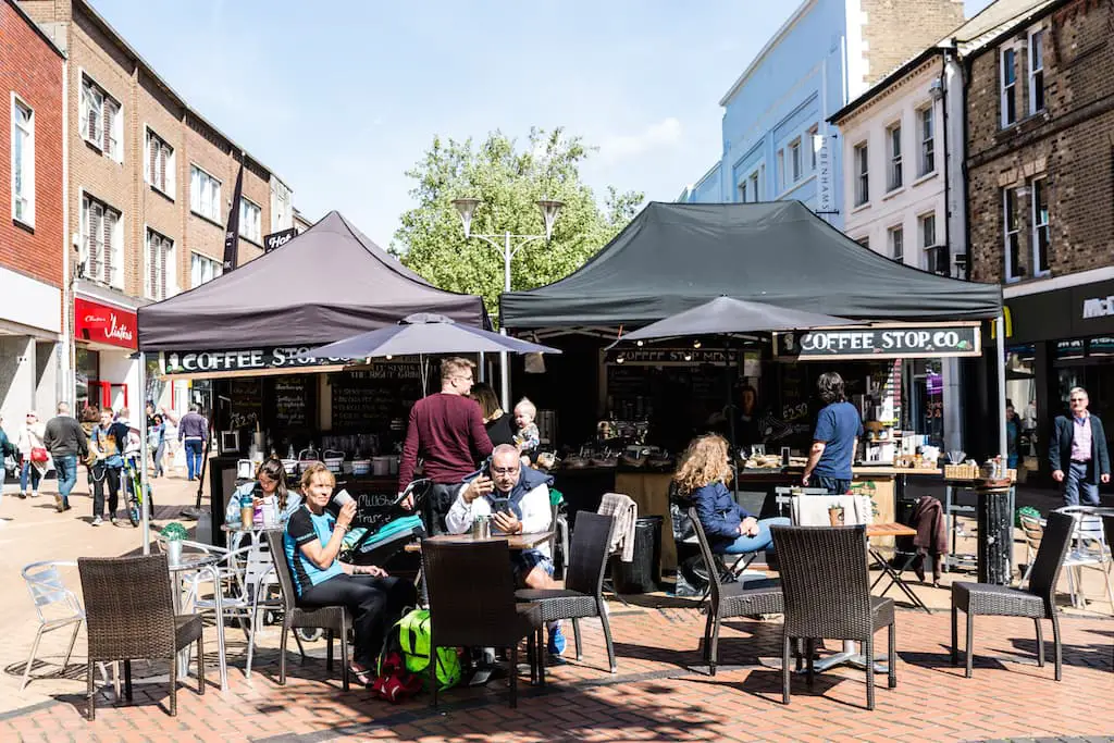 People sitting at tables by coffee stall in High Street
