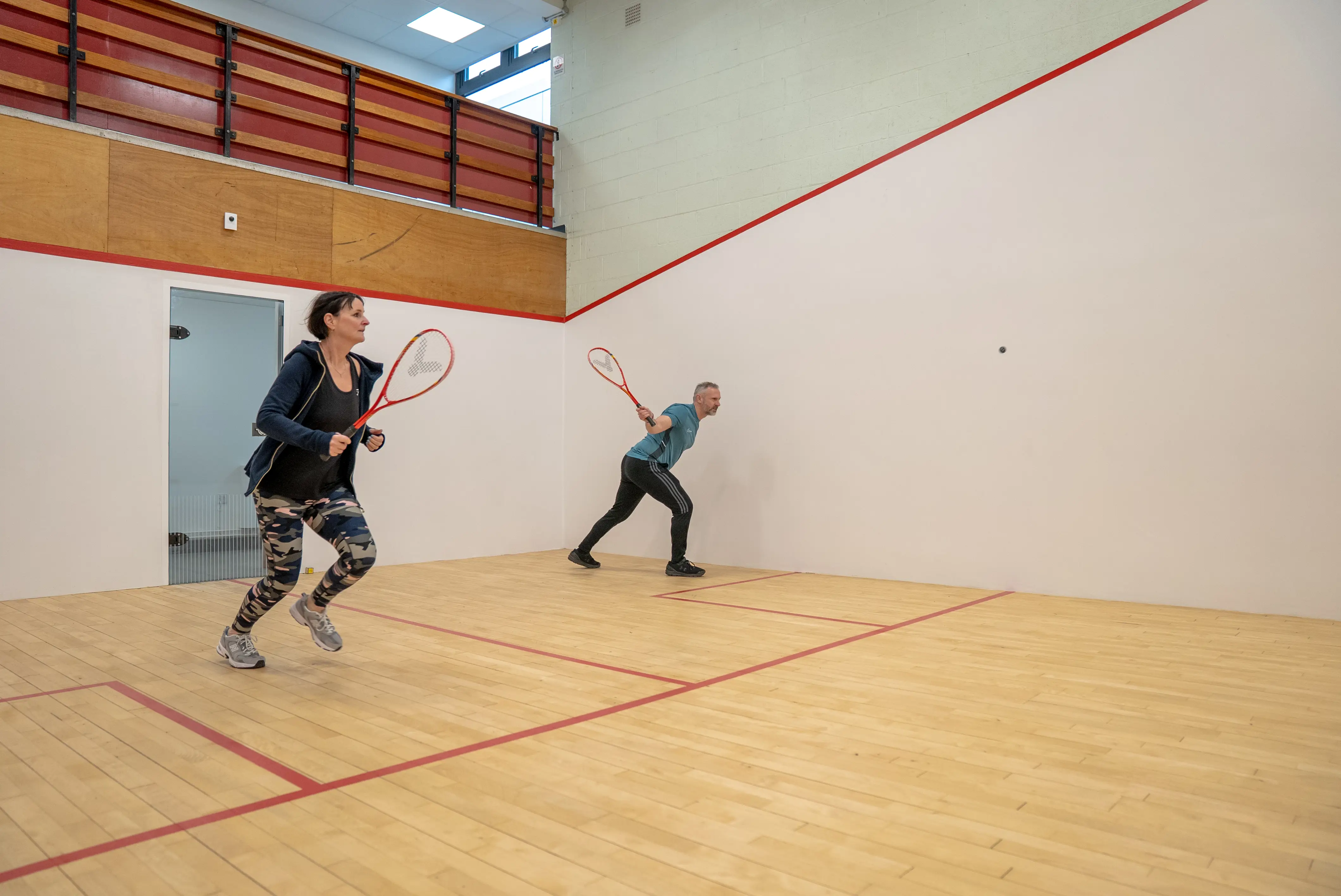 Man and woman playing on squash court
