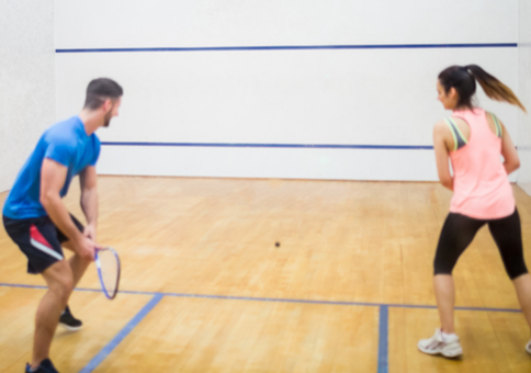 Man and woman playing on squash court