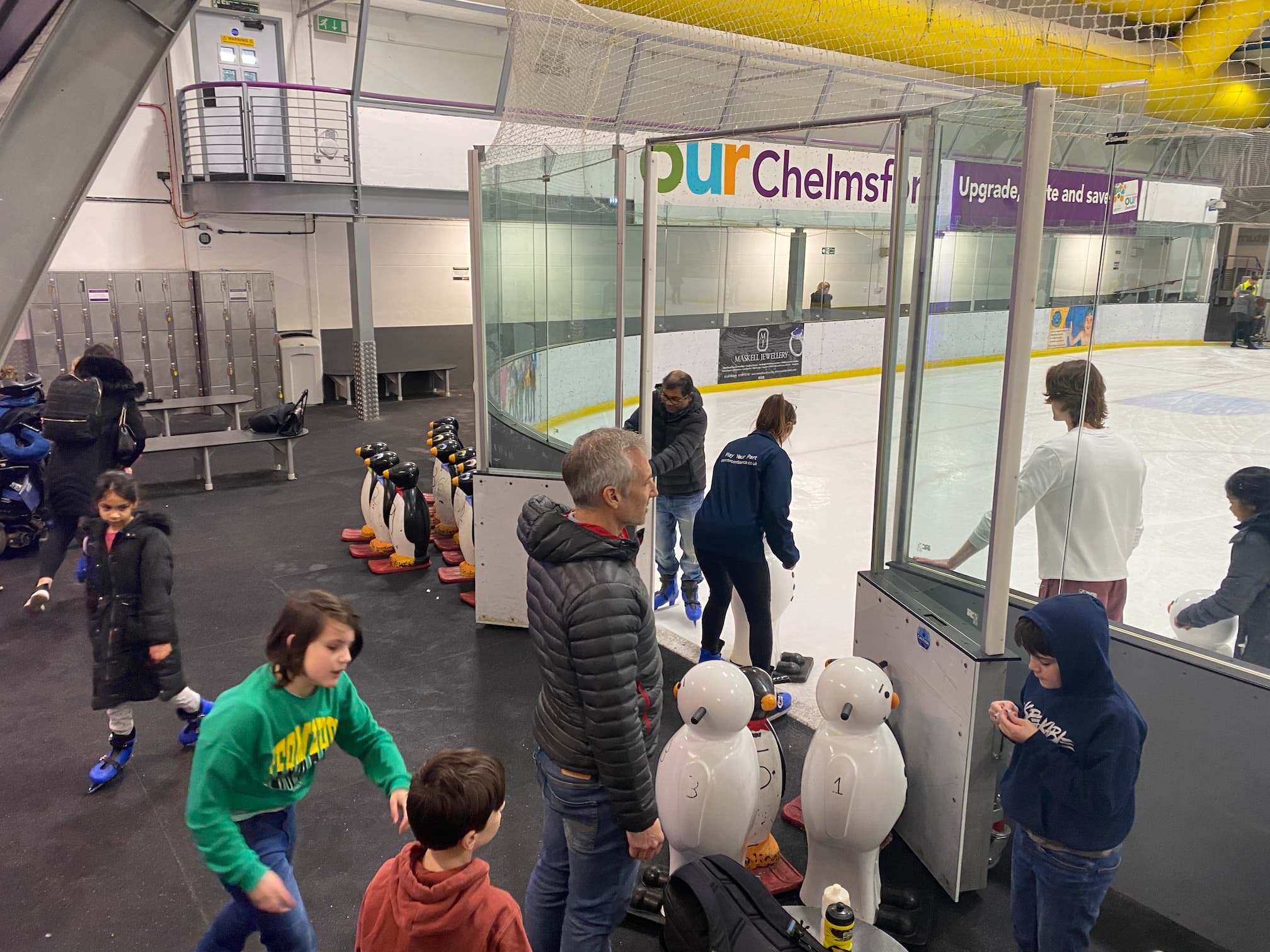 A small group of people entering an ice skating rink
