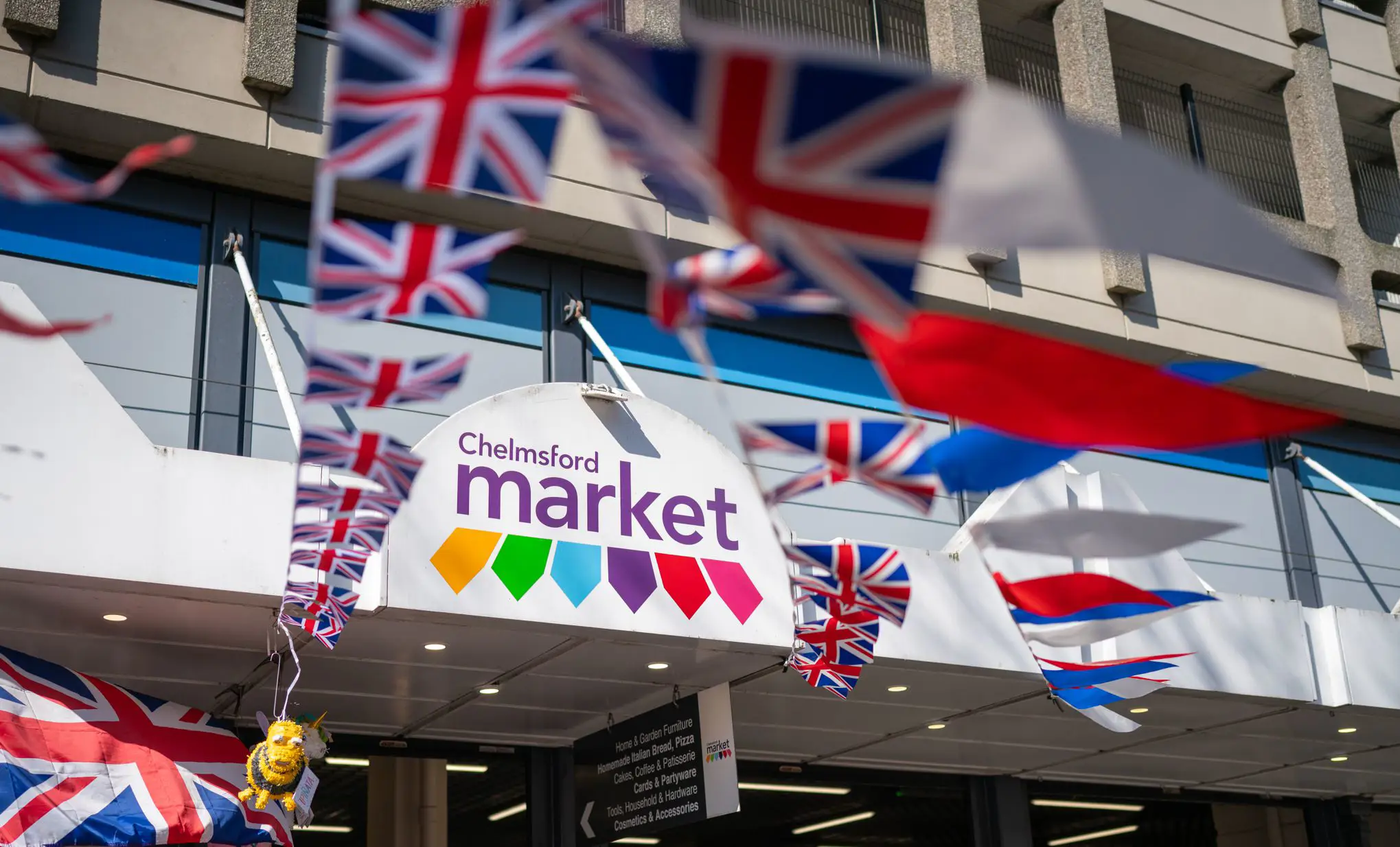 Front canpoy of Chelmsford market, featuring its logo, with Union Flag bunting string around the entrance