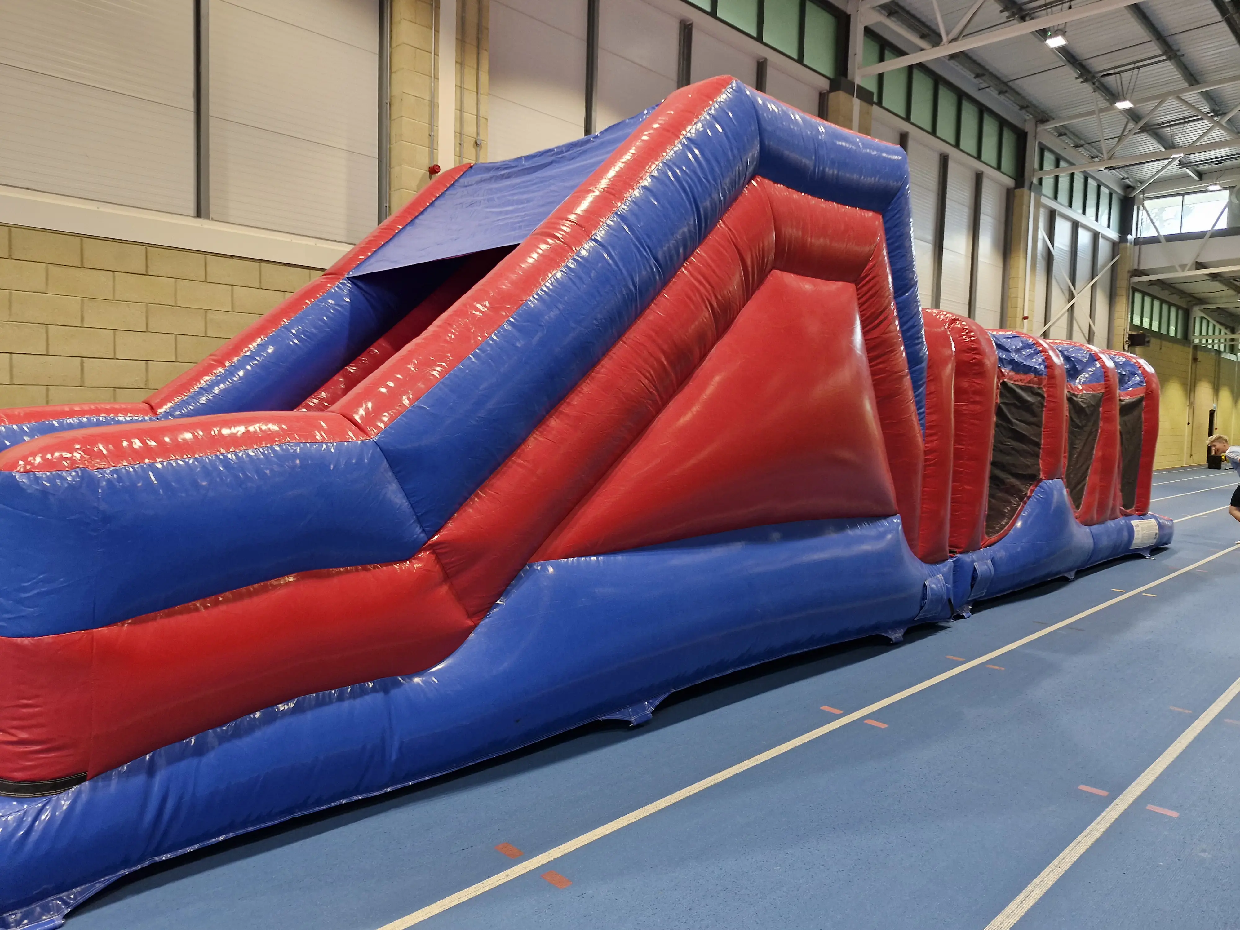 Large red and blue inflatable play equipment in sports hall