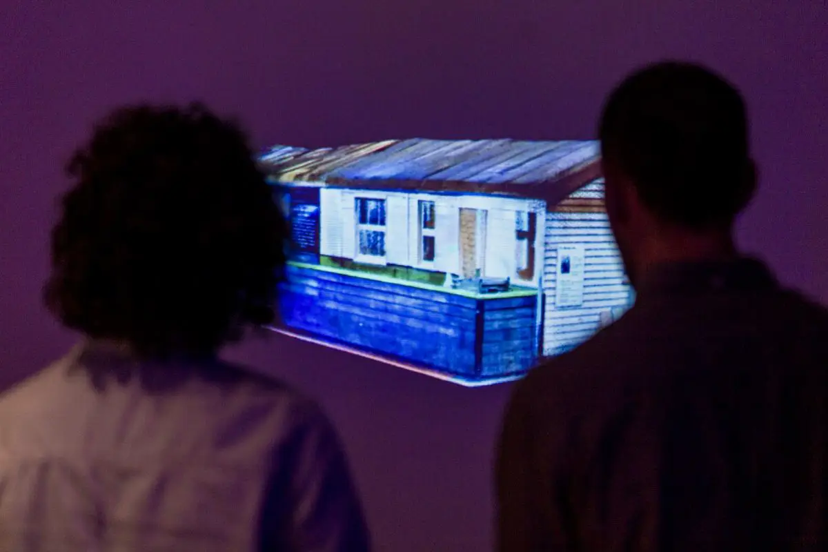 Two people standing in front of a screen with a projection of the scan of the Writtle Hut. 