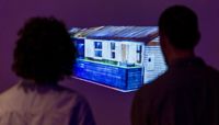 Two people standing in front of a screen with a projection of the scan of the Writtle Hut.  preview