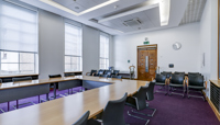 Meeting room set out with large boardroom-style layout, plus seating for small audience preview