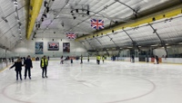 Group of people ice skating on an indoor ice rink preview