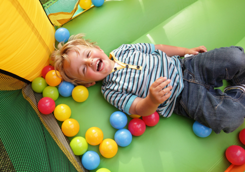 Laughing boy in soft play ball pit