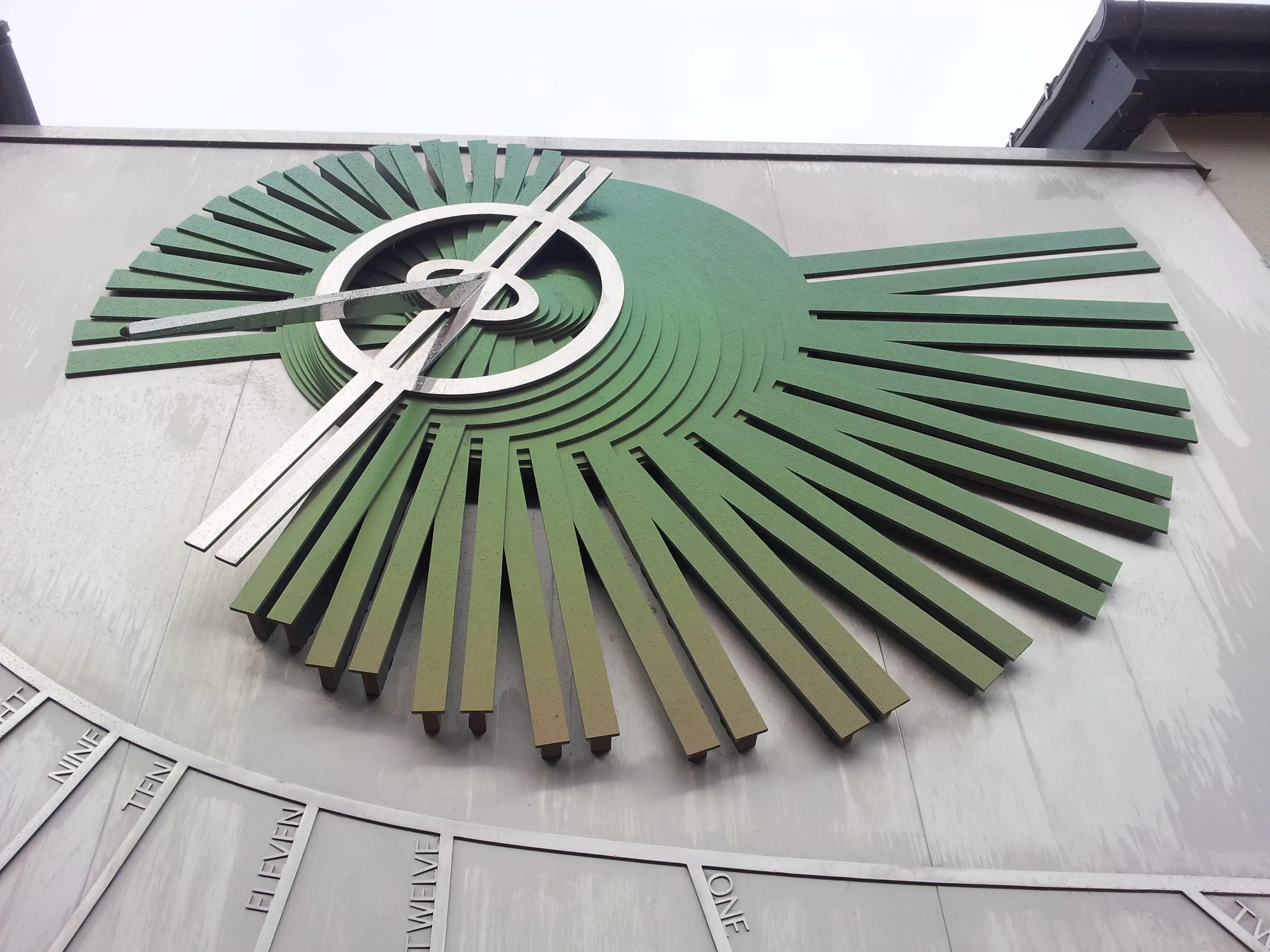 Sculpture of stylised sundial on the side of a building