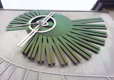 Sculpture of stylised sundial on the side of a building