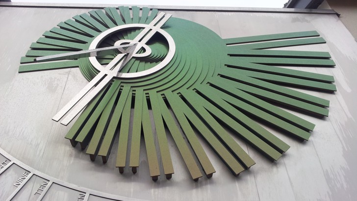 Sculpture of stylised sundial on the side of a building