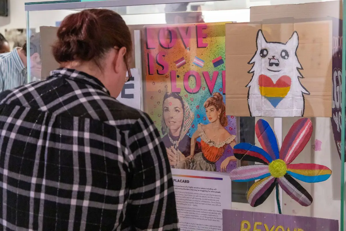 A person looking at a display of the Behind the Rainbow exhibition. 