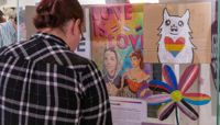 A person looking at a display of the Behind the Rainbow exhibition.  preview