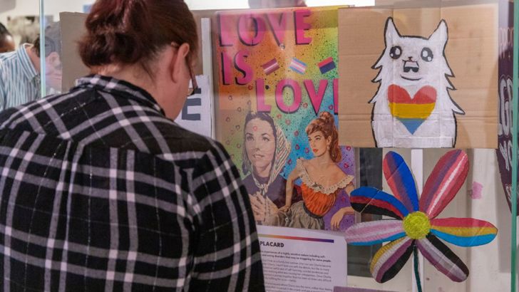A person looking at a display of the Behind the Rainbow exhibition. 