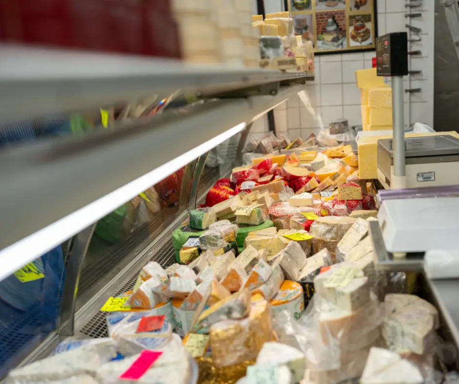Large variety of different cheeses on display behind a counter
