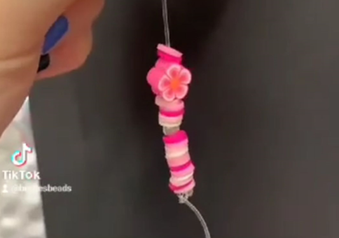 TikTok still showing pink beads being threaded with caption "create whatever pattern you come up with!"