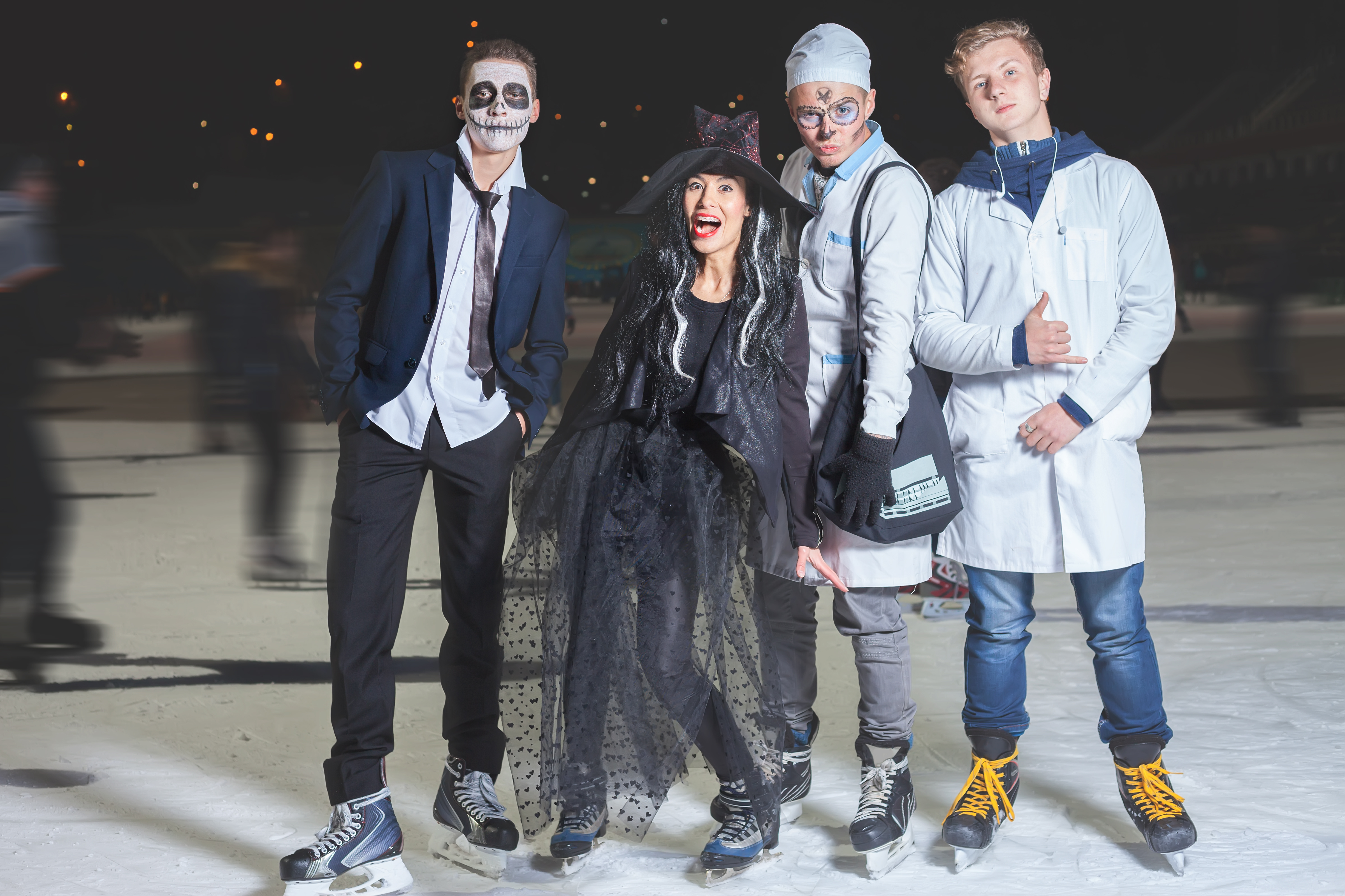 Four people on ice rink dressed up in Halloween costumes