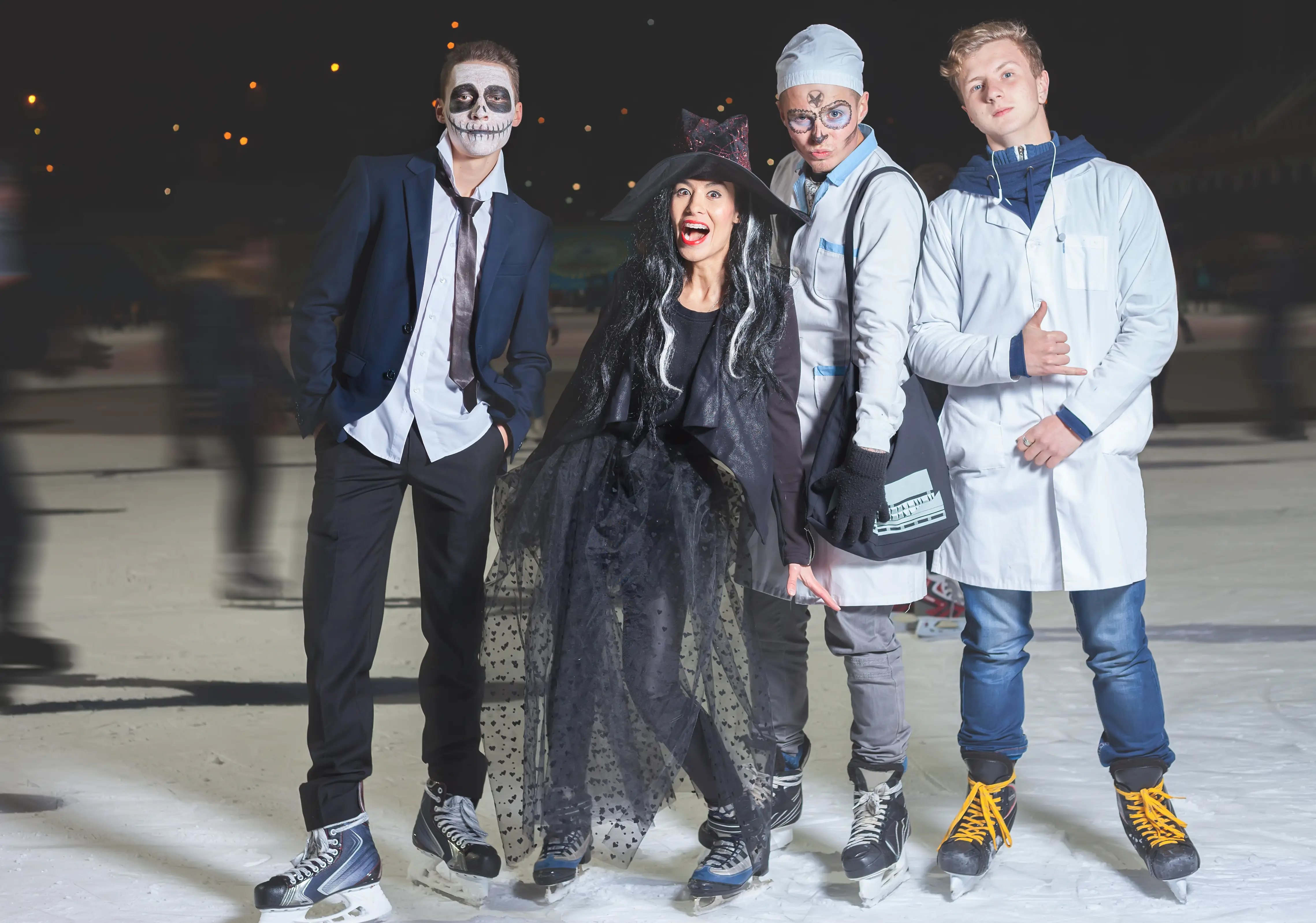 Four people on ice rink dressed up in Halloween costumes