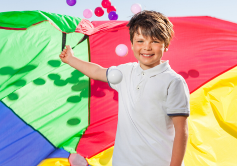 Boy playing with multi-coloured parachute and balls
