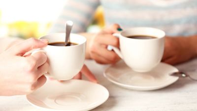 A close up of two people holding tea cups. 