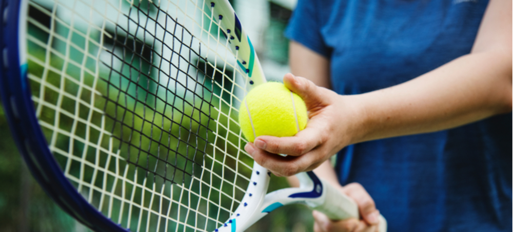 Person holding tennis racket and yellow tennis ball