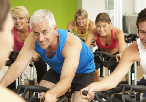 A group of adults participate in a cycling exercise class