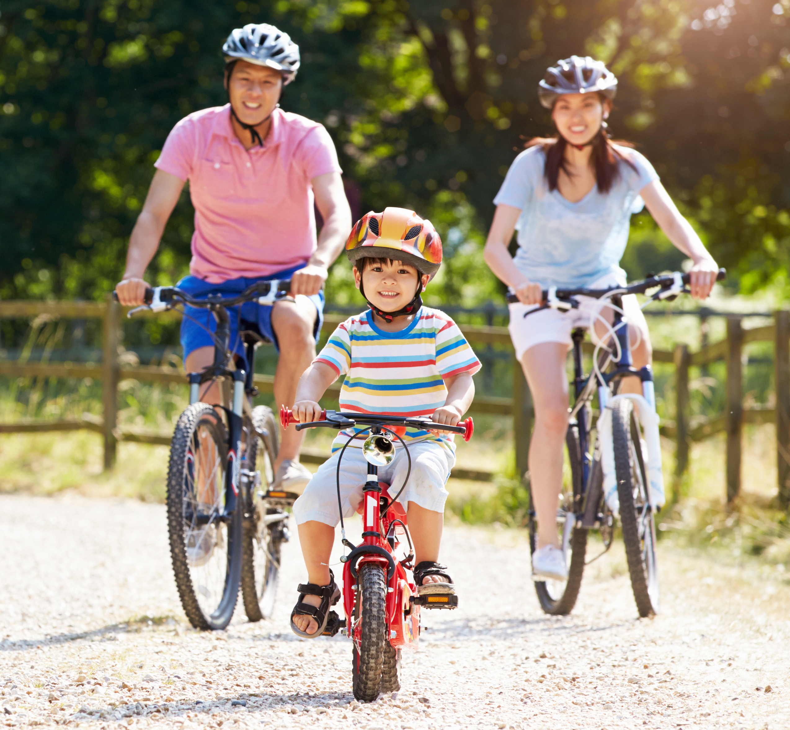 Family on bikes cycling along gravel path in Summer