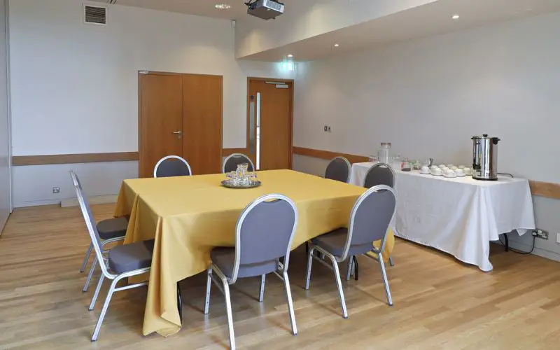 The Wells Suite set up with one table for eight people and a coffee station off to the side.