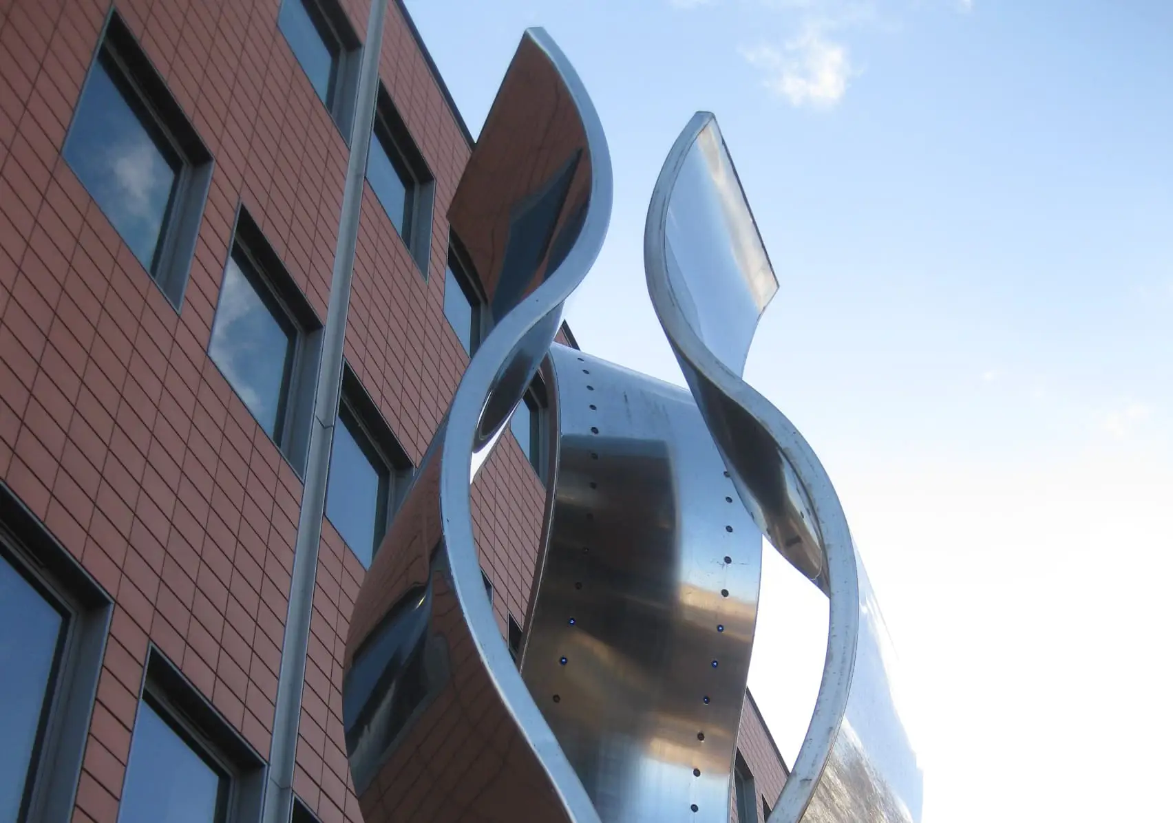 Statue featuring three large, vertical, stainless-steel ribbons, one with blue LED lights lining the inner surface