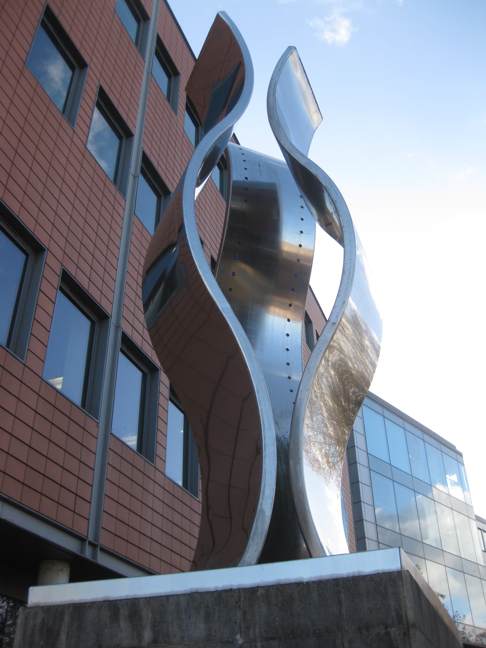 Statue featuring three large, vertical, stainless-steel ribbons, one with blue LED lights lining the inner surface