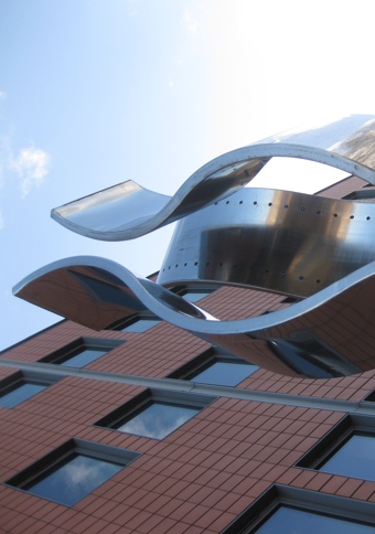 Statue featuring three large, vertical, stainless-steel ribbons, one with blue LED lights lining the inner surface