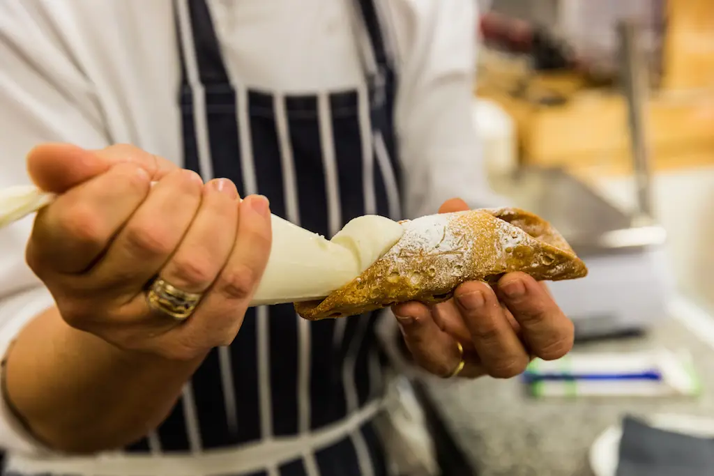 Stall holder filling sweet treat with cream