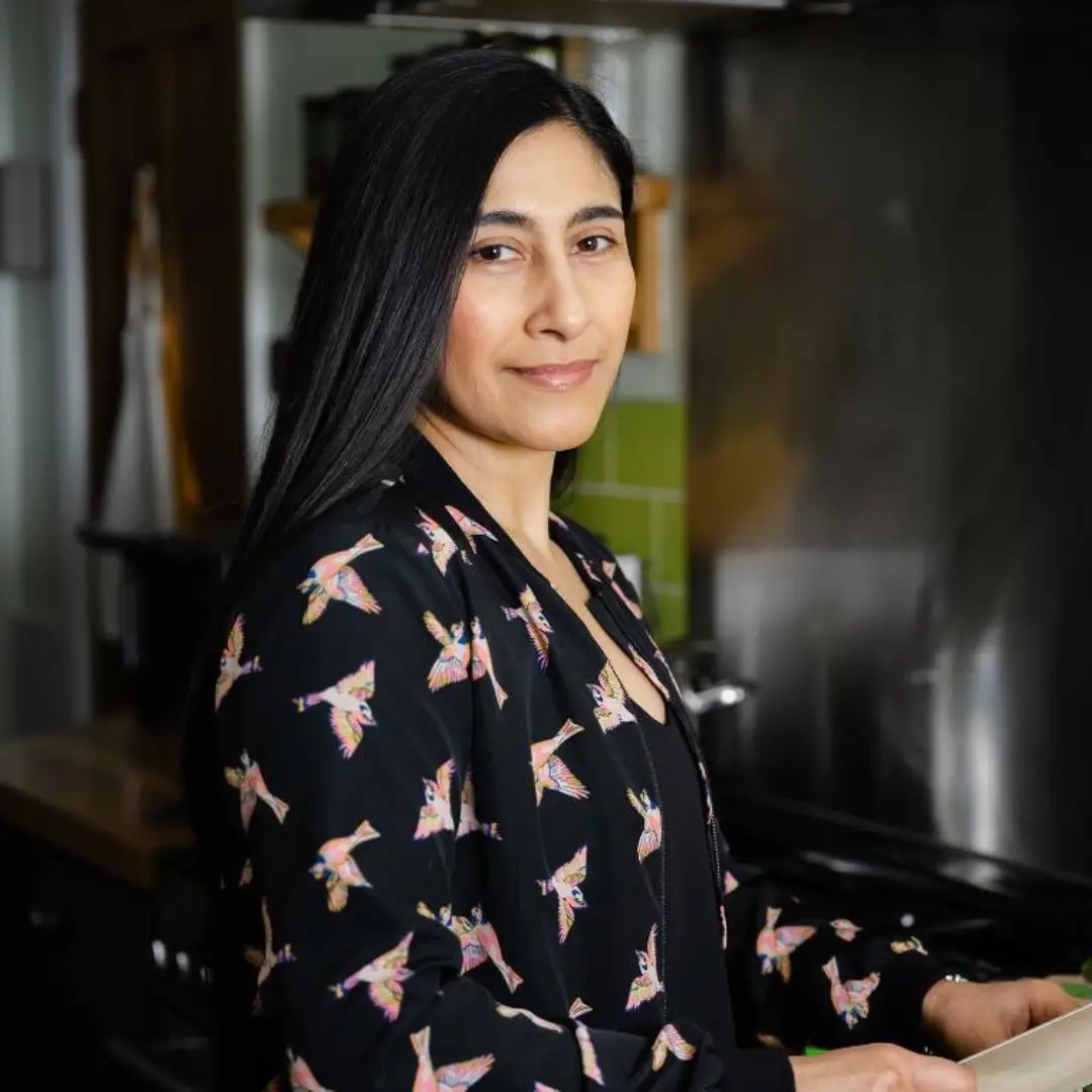 Woman with long dark hair wearing dark blue blouse with birds on it