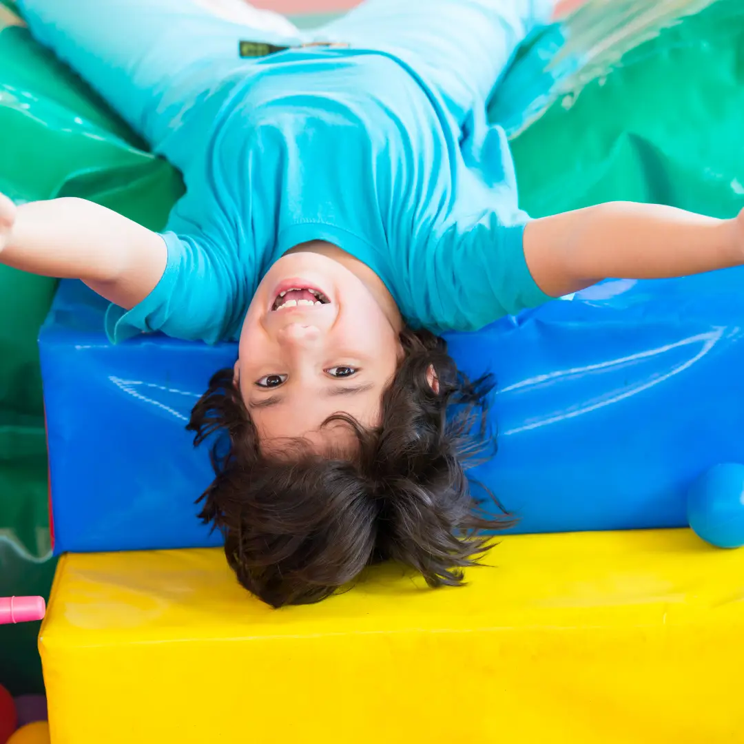 Smiling boy laying on colourful soft play cushions