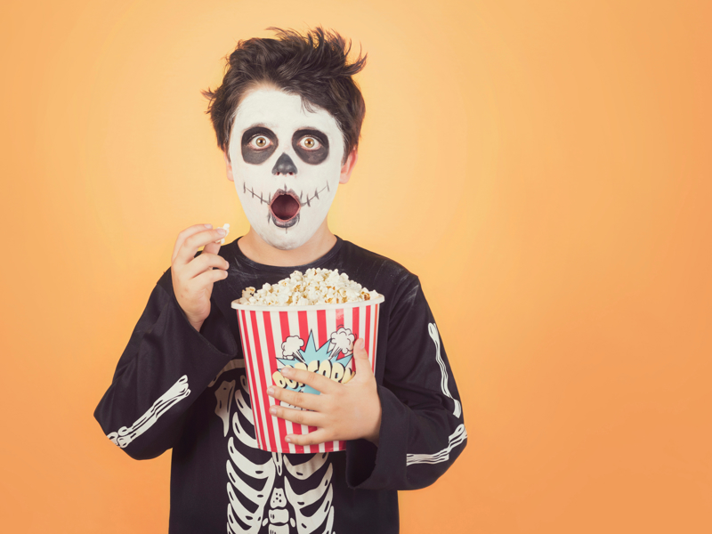 Young boy in skeleton fancy dress eating popcorn