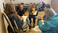 A group of kids at Radio Club sit in a circle working on their scripts.  preview