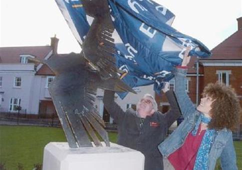 Two women unveiling a sculpture of a bird on a plinth
