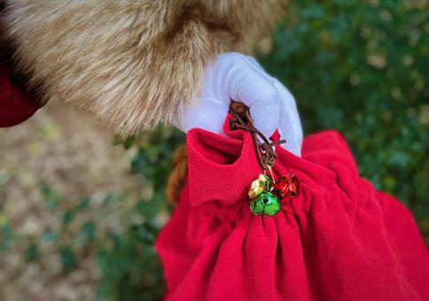Father Christmas' hand in white glove holding a large red sack