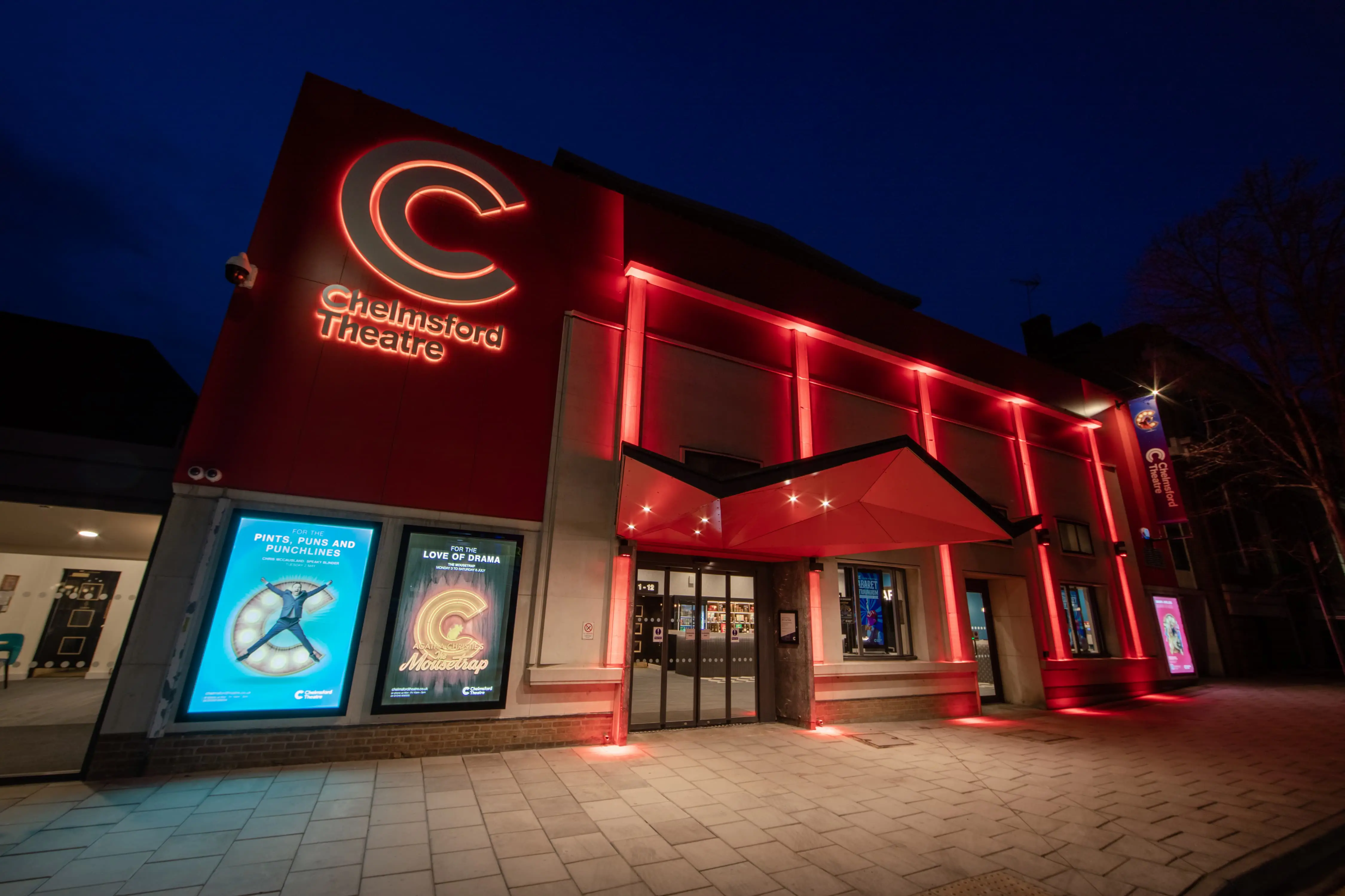 Chelmsford Theatre at night, with frontage lit up in red