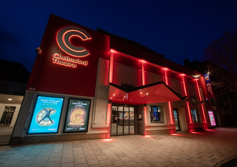 Chelmaford Theatre at night, with frontage lit up in red