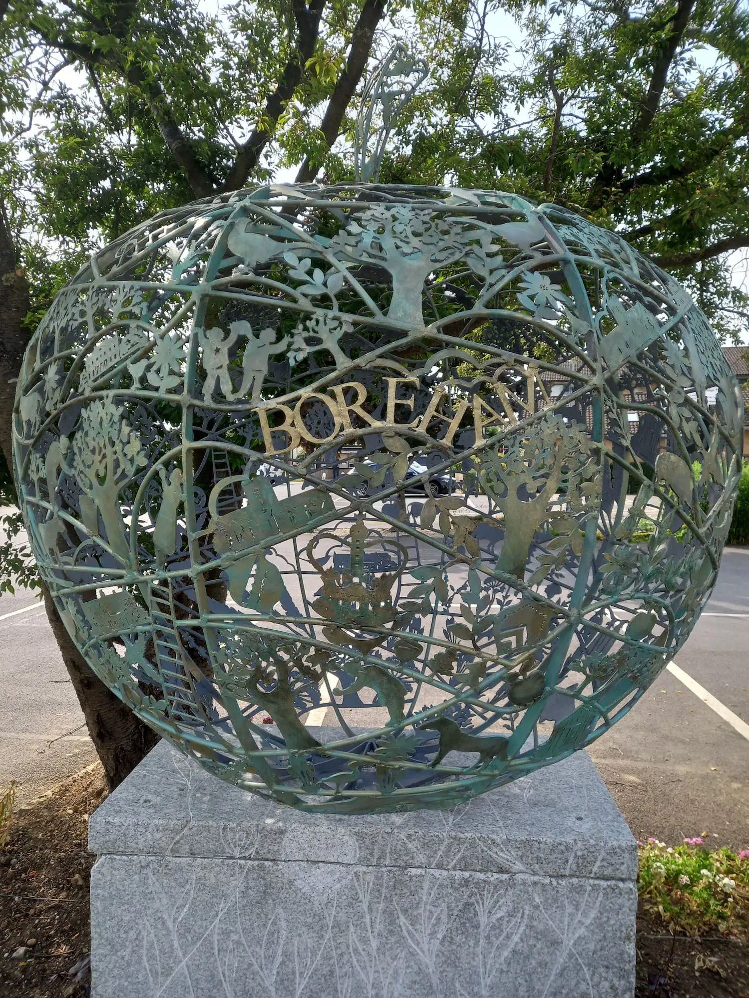 Large art installation in the shape of an apple, made of intricately arranged copper pieces