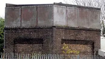 Brick tower with metal top behind metal railings (Photograph courtesy and copyright © Stuart Axe)