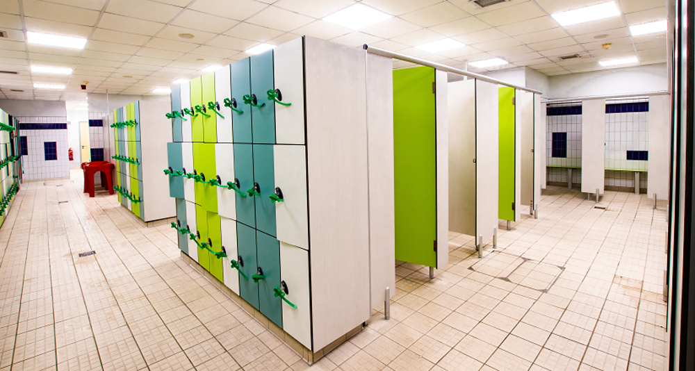 Changing room with green lockers and cubicles