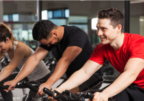 Three people take a group cycling class