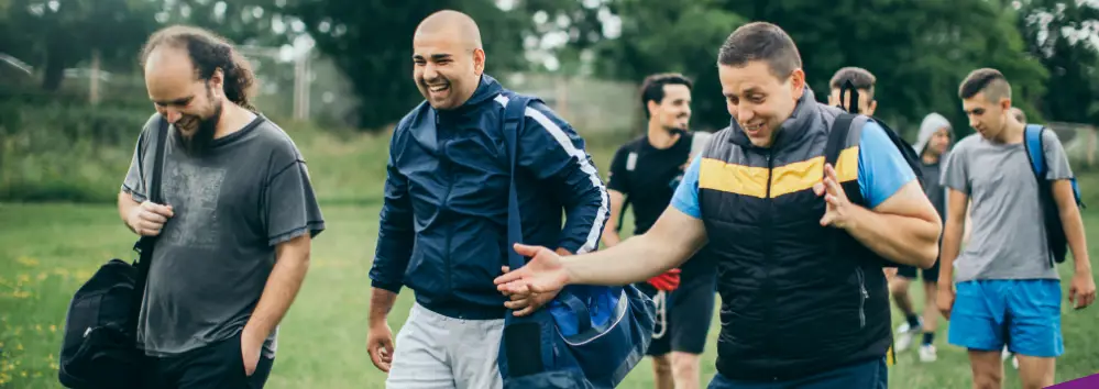 We are On Your Team (group of men walking on to field with kit bags)
