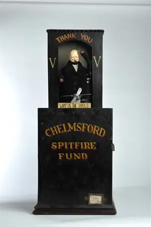 Black collection box for Chelmsford Spitfire Fund, featuring small model of Winston Churchill