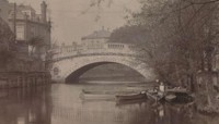 Small wooden boats on river in front of bridge with large single arch (old black and white photo) preview